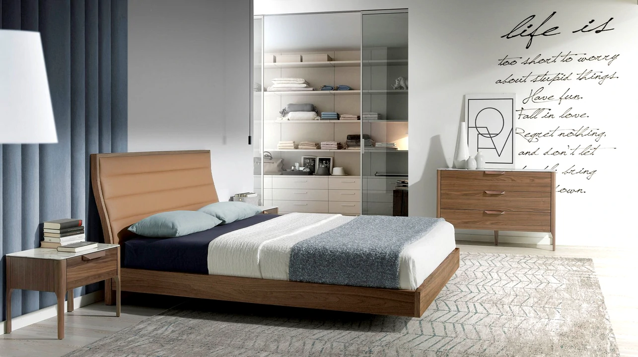 Cama estofada em tecido suave, em tons pastel, proporcionando conforto e elegância ao quarto moderno