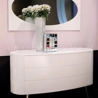 Cómoda branca oval com espelho redondo, jarro de flores e caixa espelhada.