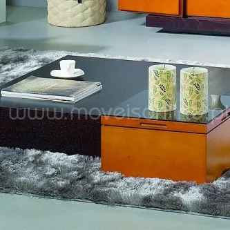 Mesa de centro baixa com tampo de vidro preto e gaveta laranja sobre tapete cinzento
