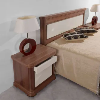 Mesa de cabeceira Mistic em madeira castanha junto à cama com candeeiro