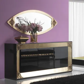 Aparador preto lacado com detalhes dourados, espelho oval e arranjo de flores.