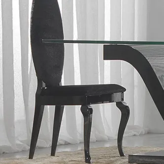 Cadeira Noir preta de costas altas e pernas curvas junto a mesa de vidro