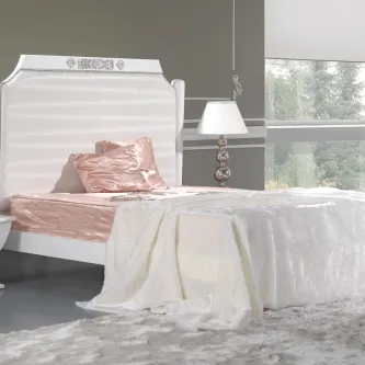 Cama Sweet branca com cabeceira alta ornamentada, roupa de cama branca e almofada rosa.