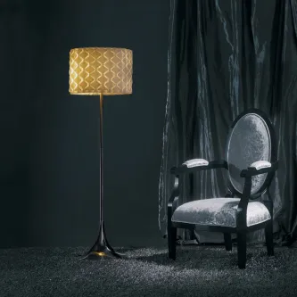 Cadeirão Platinium em veludo cinzento com estrutura preta junto a candeeiro de pé dourado