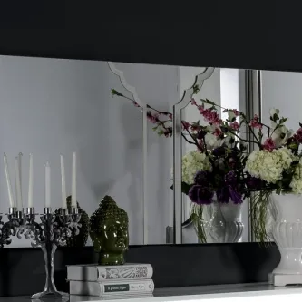 Espelho Inox Line retangular sobre aparador com candelabro, cabeça de Buda, livros e vaso de flores