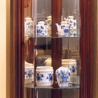 Vitrine de canto em madeira com loiça azul e branca em prateleiras de vidro