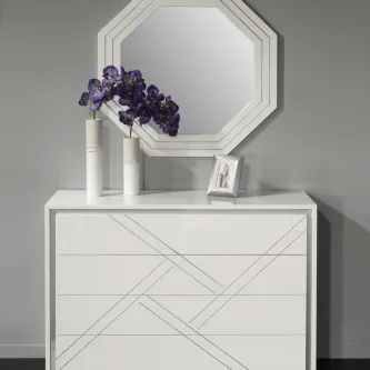 Cómoda branca com espelho losango, vasos com flores roxas e moldura