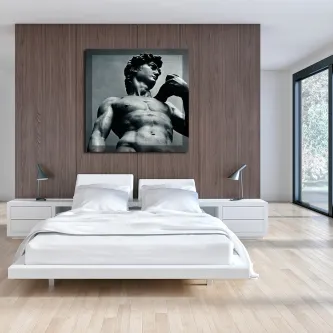 Quarto com cama branca e quadro de David em fotografia preto e branco sobre parede de madeira