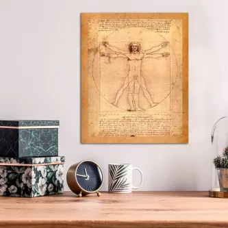 Quadro Vitruviano pendurado sobre secretária com relógio, caneca e caixas decorativas