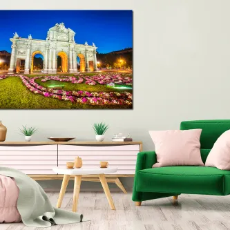 Puerta de Alcalá em Madrid iluminada à noite com jardim florido em primeiro plano
