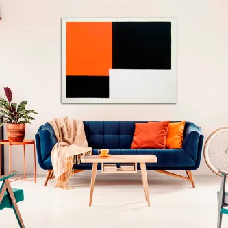 Quadro geométricos laranja com blocos laranja, preto e branco pendurado sobre sofá azul