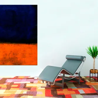 Quadro laranja com fundo azul escuro numa sala com espreguiçadeira, tapete e planta