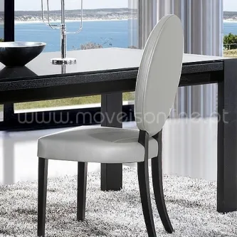 Cadeira Carrara estofada bege com costas oval e pernas negras, junto a mesa de jantar
