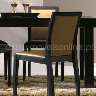 Cadeira Olympic com moldura preta e estofado dourado junto a mesa de jantar