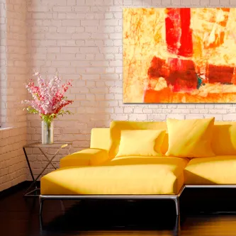 Quadro Coisa Castanha abstrato em tons laranja e vermelho sobre parede branca, acima de sofá amarelo