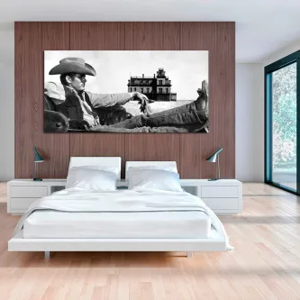 Quadro a preto e branco de homem de chapéu de cowboy reclinado com casa ao fundo