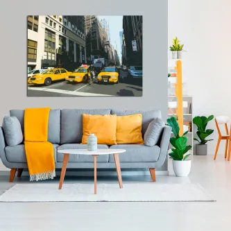 Quadro Manhattan 2 com cena urbana e táxis amarelos pendurado acima do sofá