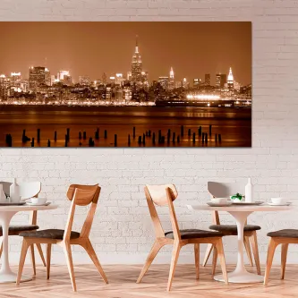 Quadro cidade noturna com horizonte urbano iluminado em sépia sobre parede branca