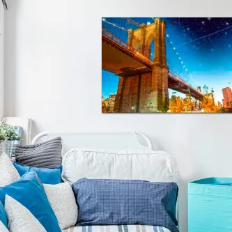 Quadro New York Cintilante com ponte iluminada sobre água na parede de uma sala