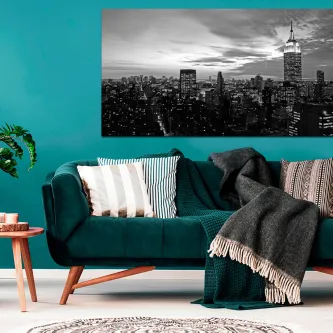 Quadro preto e branco de Nova Iorque ao anoitecer sobre parede turquesa e sofá verde