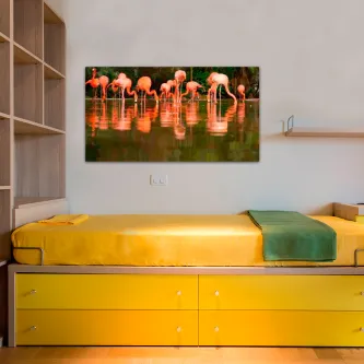 Quadro com flamingos rosados refletidos na água pendurado sobre cama amarela