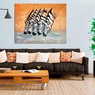 Quadro com zebras a beber num lago, pendurado acima de um sofá