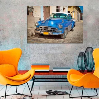Quadro com carro cubano azul estacionado numa rua, pendurado sobre poltronas laranja