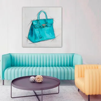 Quadro com ilustração de mala azul pendurado acima de sofá turquesa.