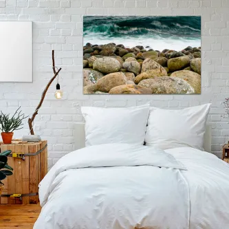 Quarto com cama branca e quadro 'Pedras à Beira Mar' com rochas e mar