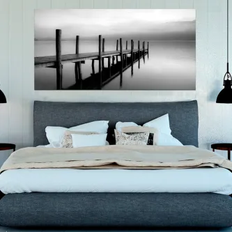 Cais de madeira sobre águas calmas em fotografia preto e branco