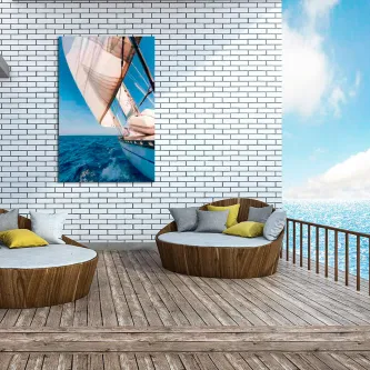 Quadro lateral de veleiro com vela e mar, pendurado numa parede branca numa varanda