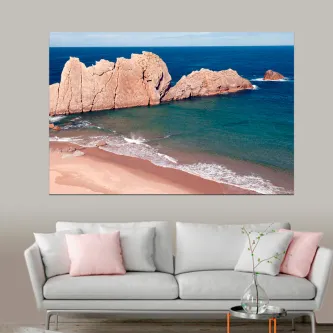 Quadro de rochas no mar pendurado sobre um sofá cinzento com almofadas cor-de-rosa