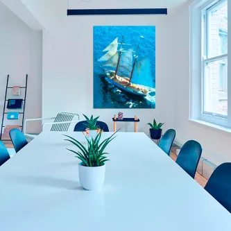 Quadro com barco visto de cima sobre mar azul, pendurado numa sala de reuniões