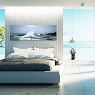 Quadro com ondas a rebentar sobre rochas, pendurado acima de cama moderna