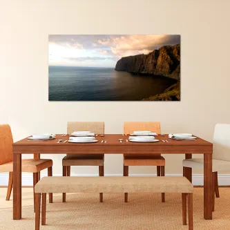 Quadro Costa Marítima com falésia rochosa e mar calmo ao pôr do sol acima de mesa de jantar