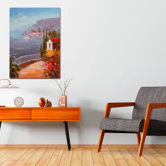 Quadro de aldeia à beira-mar com casas coloridas, flores e mar visível, pendurado numa sala.