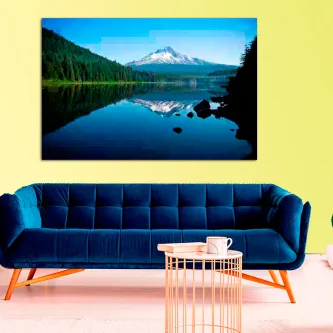 Quadro reflexo montanhoso com montanha refletida num lago sobre sofá azul