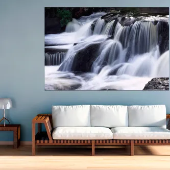 Quadro Lances de Água mostrando cascata a cair sobre rochas acima de um sofá