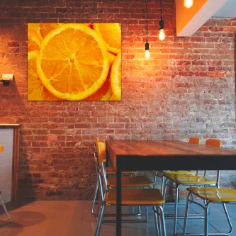 Quadro rodela de laranja pendurado em parede de tijolo sobre mesa e cadeiras
