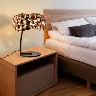 Candeeiro de mesa Narisa dourado com abajur escultural em criado-mudo ao lado da cama
