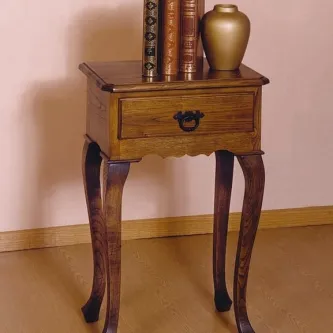 Mesa de apoio Veneza em madeira escura com gaveta e pés curvos, decorada com livros e vaso.