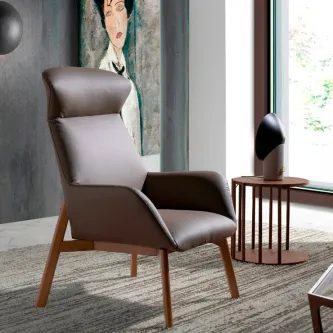 Poltrona Chen em pele castanha com encosto alto e pés de madeira junto a mesa lateral
