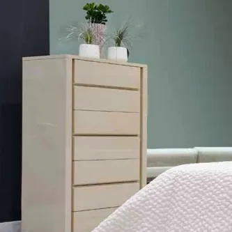 Camiseiro Alfaiate II de madeira clara junto à cama com plantas no topo
