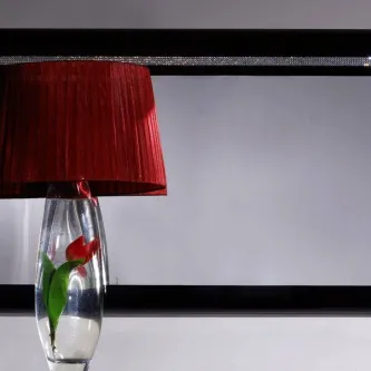 Espelho Diamond retangular com moldura preta que reflete candeeiro com abajur vermelho