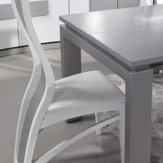 Cadeira Galaxie branca com encosto curvo e assento estofado junto a mesa cinzenta