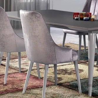 Cadeira Charlotte estofada em veludo cinzento junto a mesa de jantar