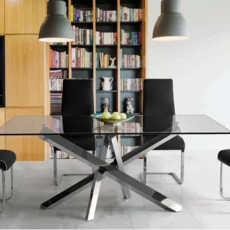 Mesa de vidro Milan com base metálica cruzada e cadeiras pretas em sala com estante