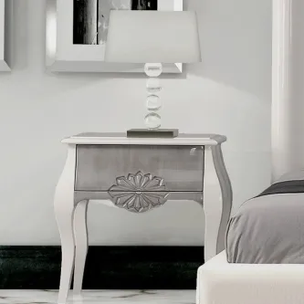 Mesa de cabeceira branca de 1 gaveta com entalhe floral e candeeiro sobre o tampo