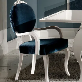Cadeirão Nila branco com estofado azul-escuro em veludo, braços curvos e pernas torneadas