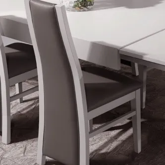 Cadeira Carrera em madeira branca com estofado cinzento junto a mesa branca